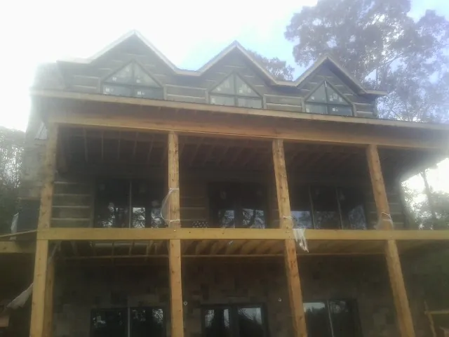 Dormers and porch framing on a large log home under construction — Roof Coating work by our crew in Brownsdale