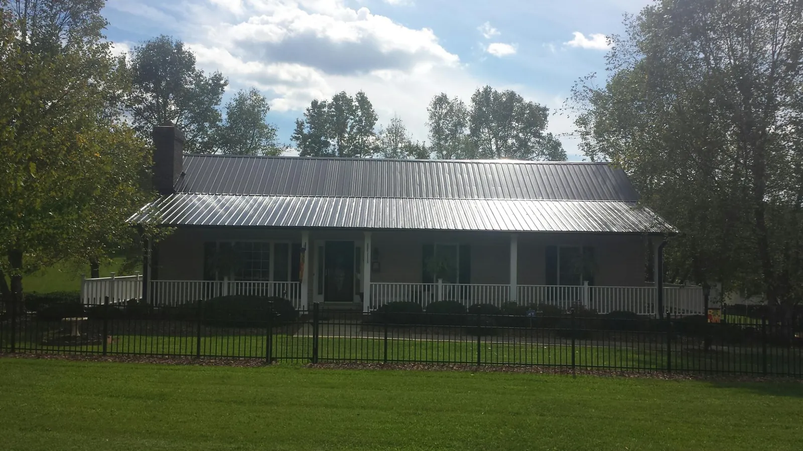Gray metal roof on a brick ranch with a full width front porch — Gutter Guard Installation work by our crew in Brownsdale