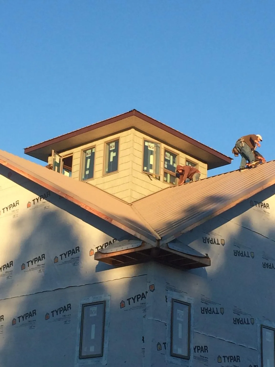 Roofers working around a rooftop cupola on a new metal roof at sunset — Roof Waterproofing in Brownsdale by Roofing Brothers